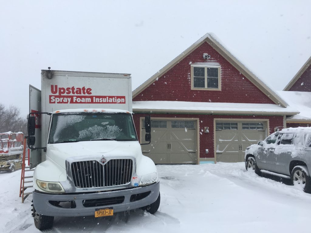 Spray foam insulation being installed in a garage during snowy winter months